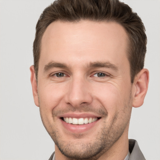 Joyful white young-adult male with short  brown hair and grey eyes