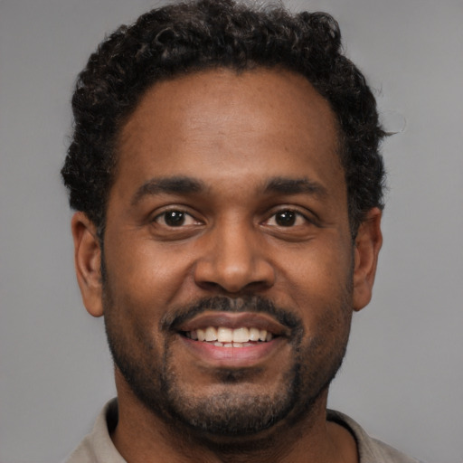 Joyful black young-adult male with short  black hair and brown eyes