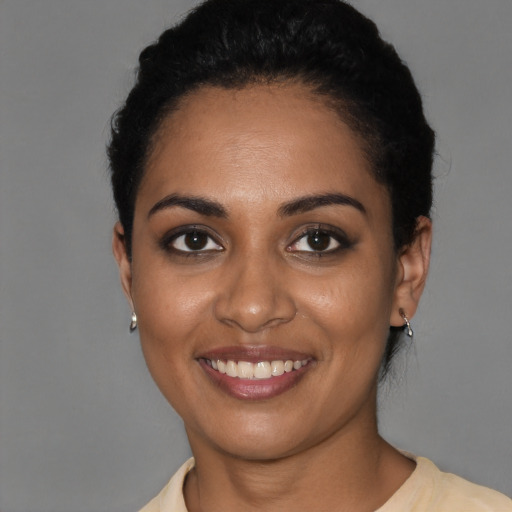 Joyful black young-adult female with short  black hair and brown eyes