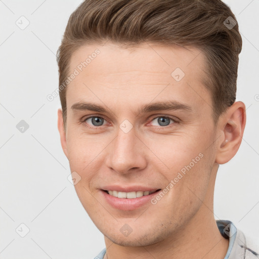 Joyful white young-adult male with short  brown hair and grey eyes