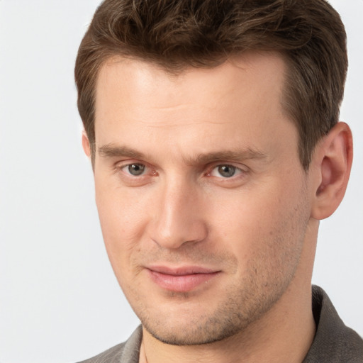 Joyful white young-adult male with short  brown hair and grey eyes