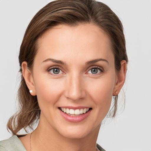 Joyful white young-adult female with medium  brown hair and grey eyes