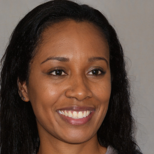 Joyful black young-adult female with long  brown hair and brown eyes