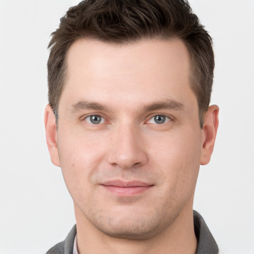 Joyful white young-adult male with short  brown hair and grey eyes