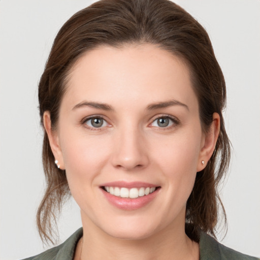 Joyful white young-adult female with medium  brown hair and grey eyes