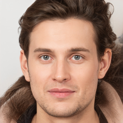 Joyful white young-adult male with long  brown hair and brown eyes