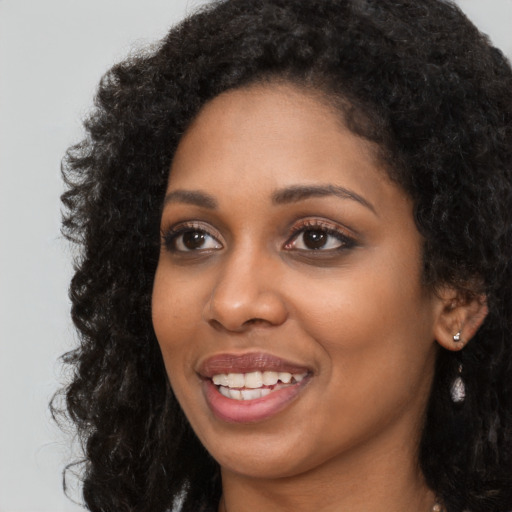 Joyful black young-adult female with long  black hair and brown eyes