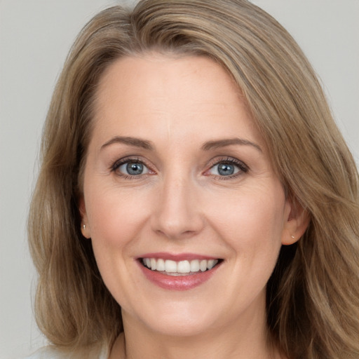 Joyful white adult female with long  brown hair and grey eyes