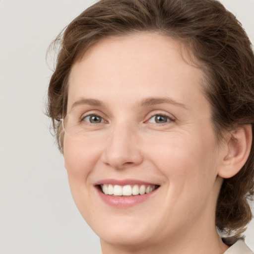 Joyful white young-adult female with medium  brown hair and green eyes