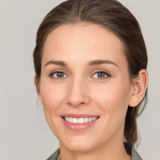 Joyful white young-adult female with medium  brown hair and grey eyes