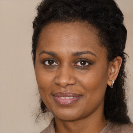 Joyful black young-adult female with long  brown hair and brown eyes