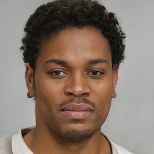 Joyful black young-adult male with short  brown hair and brown eyes