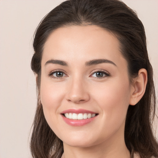 Joyful white young-adult female with long  brown hair and brown eyes