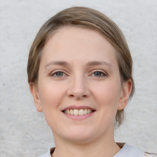 Joyful white young-adult female with medium  brown hair and grey eyes