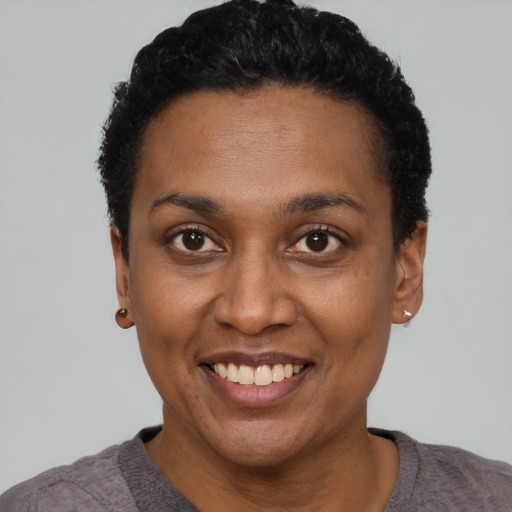 Joyful black young-adult female with short  black hair and brown eyes