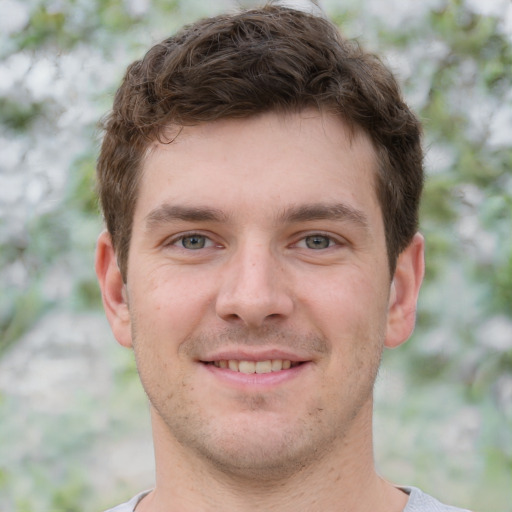 Joyful white young-adult male with short  brown hair and grey eyes