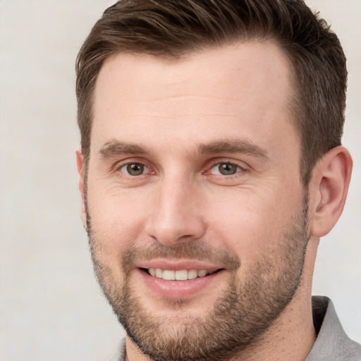 Joyful white young-adult male with short  brown hair and grey eyes