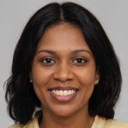 Joyful black young-adult female with long  brown hair and brown eyes