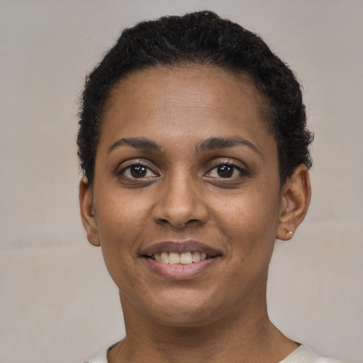 Joyful black young-adult female with short  black hair and brown eyes