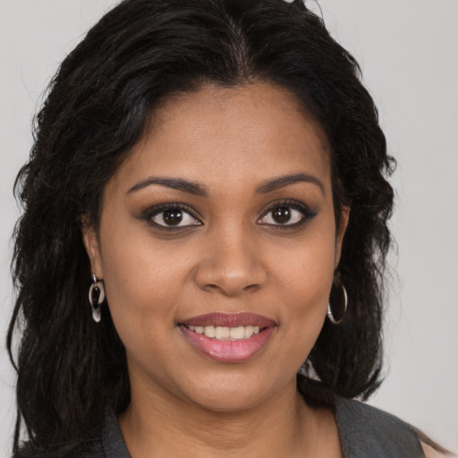 Joyful black young-adult female with long  brown hair and brown eyes