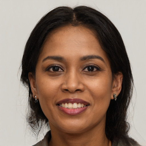 Joyful black young-adult female with long  brown hair and brown eyes