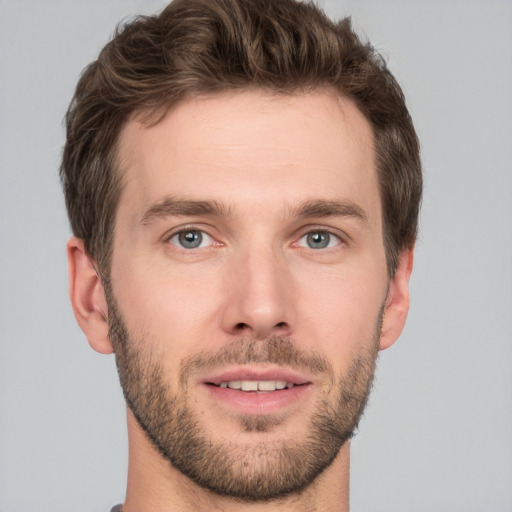 Joyful white young-adult male with short  brown hair and grey eyes