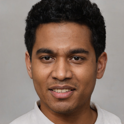Joyful black young-adult male with short  black hair and brown eyes