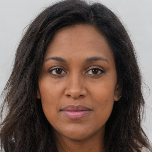 Joyful black young-adult female with long  brown hair and brown eyes