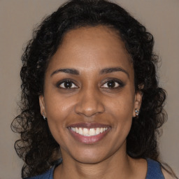 Joyful black young-adult female with long  brown hair and brown eyes