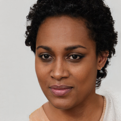 Joyful black young-adult female with short  black hair and brown eyes
