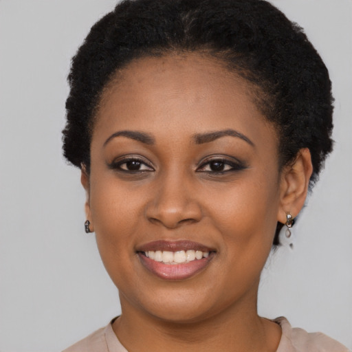 Joyful black young-adult female with short  black hair and brown eyes