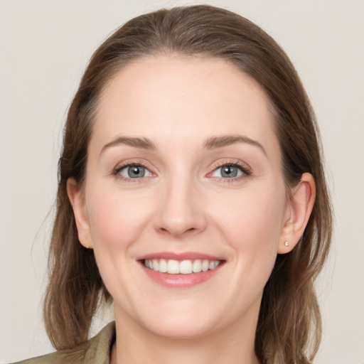 Joyful white young-adult female with medium  brown hair and grey eyes