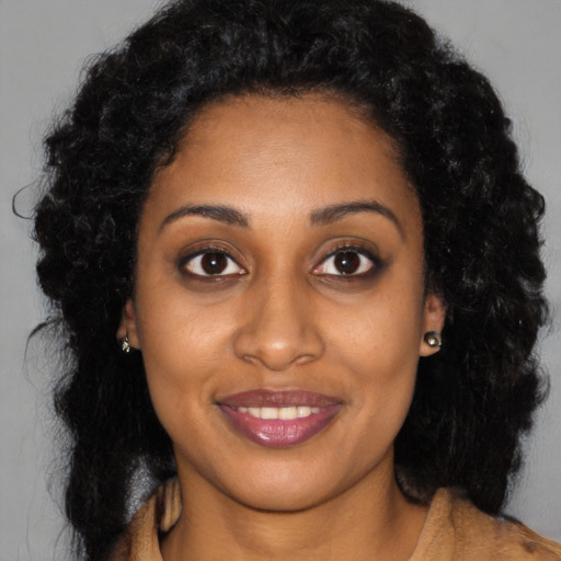 Joyful black young-adult female with long  brown hair and brown eyes