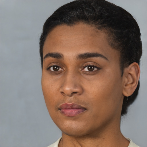 Joyful black young-adult female with short  black hair and brown eyes