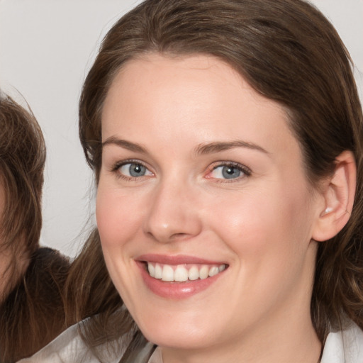 Joyful white young-adult female with medium  brown hair and grey eyes