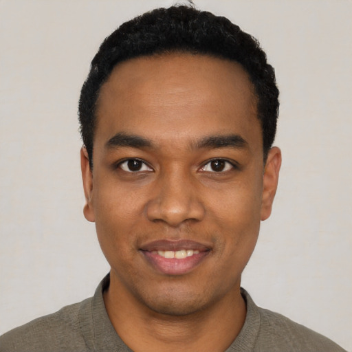 Joyful black young-adult male with short  black hair and brown eyes