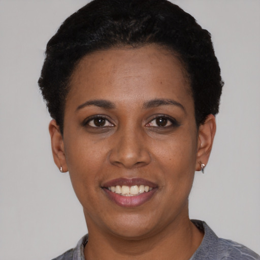 Joyful black young-adult female with short  black hair and brown eyes