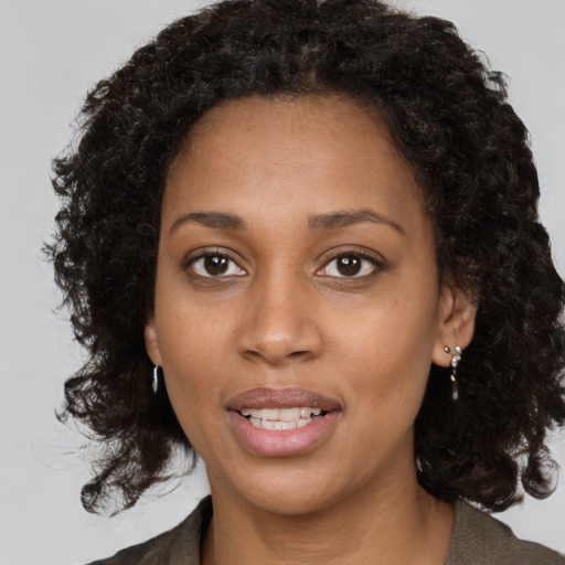 Joyful black young-adult female with long  brown hair and brown eyes