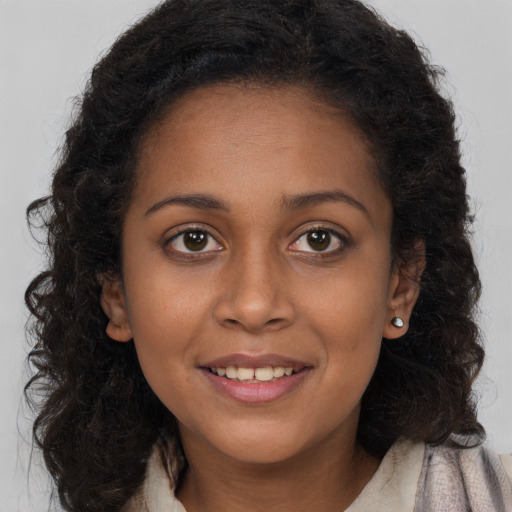 Joyful black young-adult female with long  brown hair and brown eyes