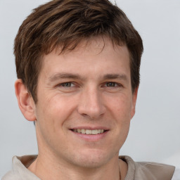 Joyful white young-adult male with short  brown hair and grey eyes