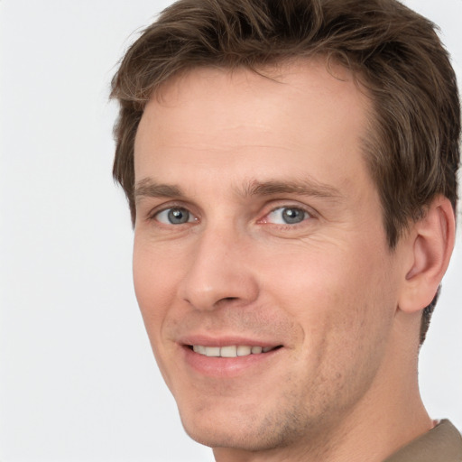 Joyful white young-adult male with short  brown hair and grey eyes