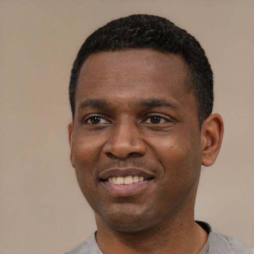 Joyful black young-adult male with short  black hair and brown eyes