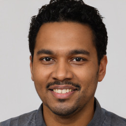 Joyful latino young-adult male with short  black hair and brown eyes
