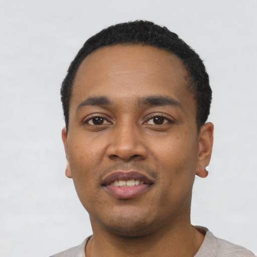 Joyful black young-adult male with short  black hair and brown eyes