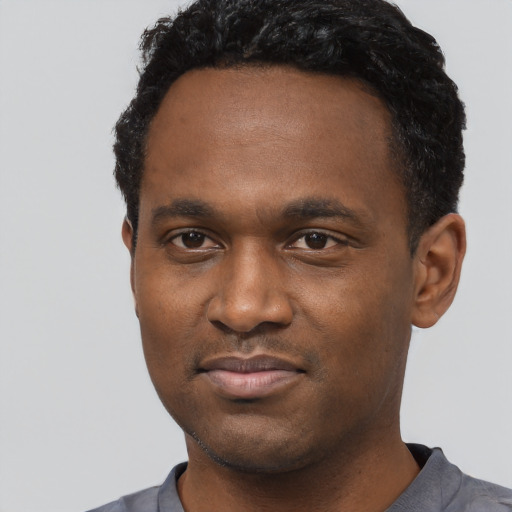 Joyful black young-adult male with short  black hair and brown eyes