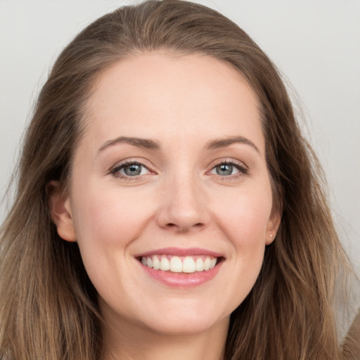 Joyful white young-adult female with long  brown hair and grey eyes