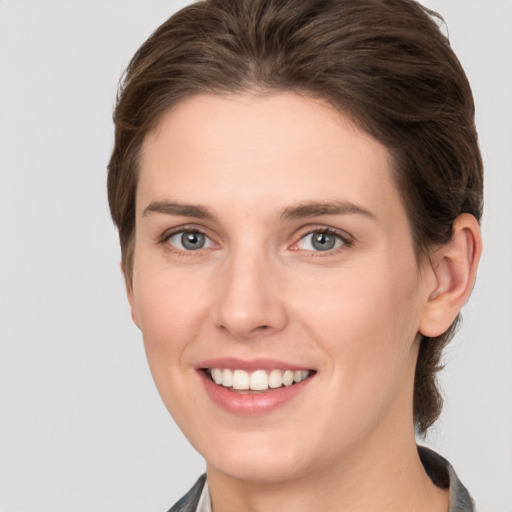 Joyful white young-adult female with medium  brown hair and grey eyes