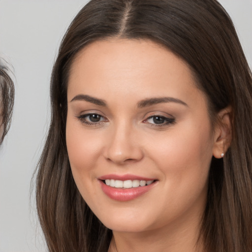 Joyful white young-adult female with long  brown hair and brown eyes