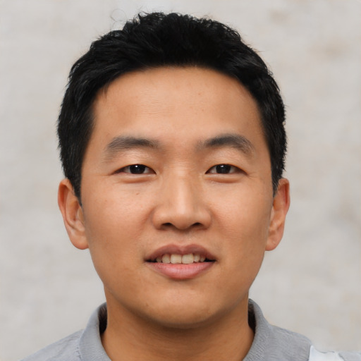 Joyful asian young-adult male with short  black hair and brown eyes