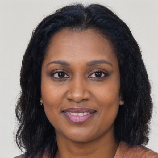 Joyful black young-adult female with long  brown hair and brown eyes